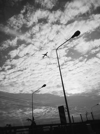 Low angle view of birds flying against cloudy sky