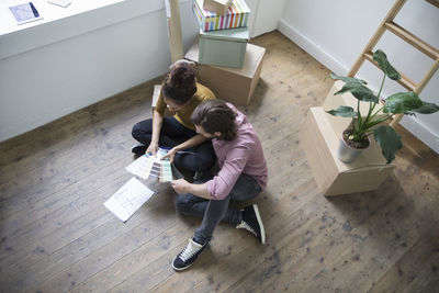 Couple sitting on floor of new flat choosing from color samples