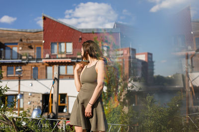 Side view of woman standing against buildings