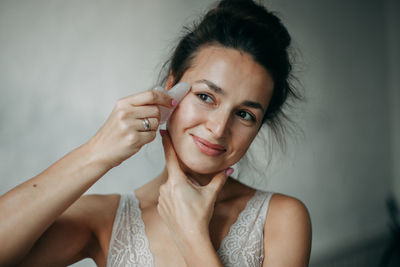 Brunette woman 30 years old doing face massage with a gouache scraper