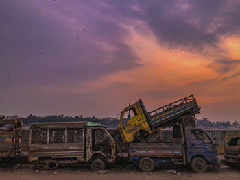 Abandoned car on field against sky during sunset