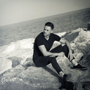 Portrait of young man sitting on rock at beach