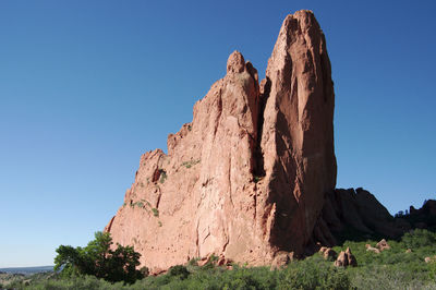 Low angle view of rock formations against clear blue sky