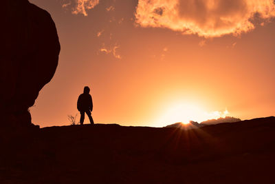 Silhouette man walking on mountain against sky during sunset