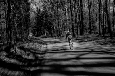 Blurred motion of person on dirt road amidst trees in forest