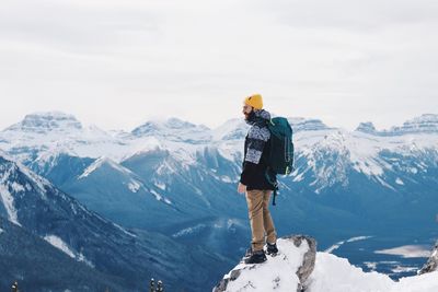 Man standing on snowcapped mountain against sky