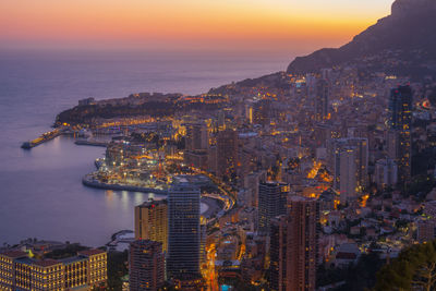 High angle view of city by sea against sky during sunset