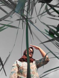 Low angle portrait of woman standing against sky