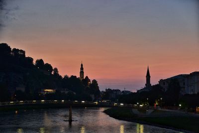 River by city against sky at sunset