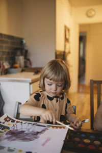 Girl sitting at table and painting