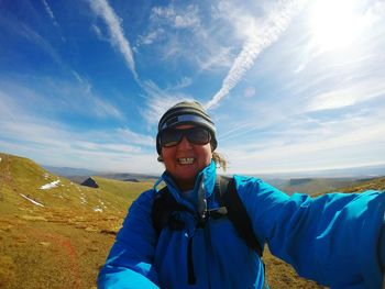 Portrait of smiling young woman standing against blue sky