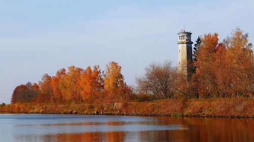 Lighthouse by lake against sky during autumn