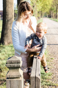 Side view of mother and daughter sitting on field