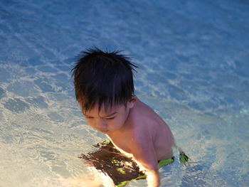 Rear view of shirtless boy on beach