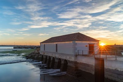 House by sea against sky during sunset