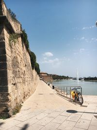 Footpath by sea in city against sky