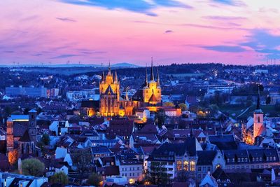 Illuminated cityscape against sky during sunset