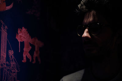 Close-up portrait of woman wearing sunglasses against black background