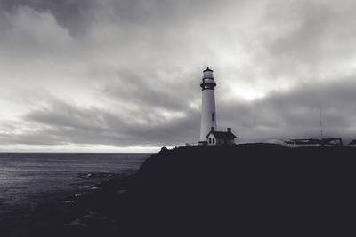 Lighthouse by sea against sky
