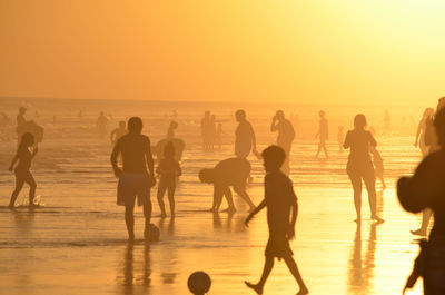 Silhouette people on beach against sky during sunset