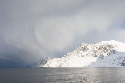 Scenic view of sea and snowcapped mountain against sky