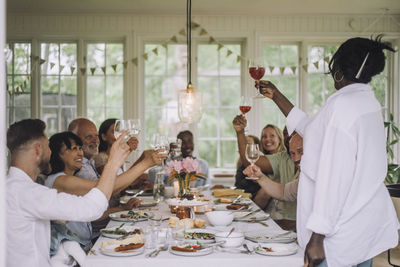 Woman toasting drinks with multi-generation family at dining table during dinner party at home