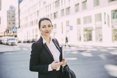 Portrait of woman with umbrella standing on road in city