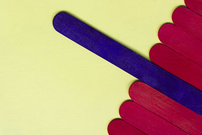 Purple and red color wooden stick on yellow background. flat lay. directly above. copy space.