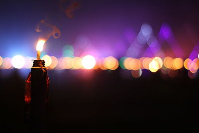 Close-up of lit oil lamp against illuminated background