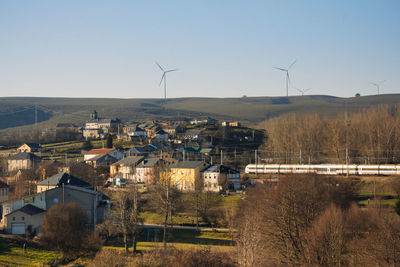 Town with wind turbines on field against sky