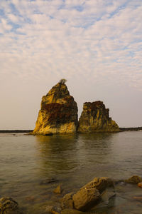 Rock formation on sea shore against sky