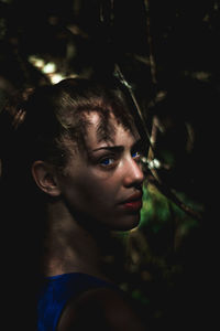 Close-up portrait of young woman by trees in forest
