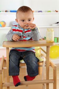 Cute boy sitting on table at home