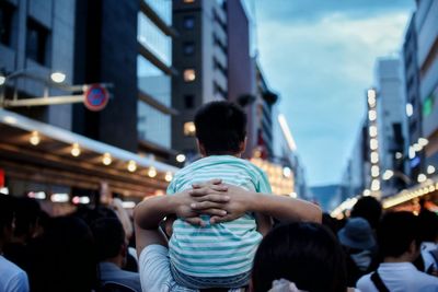 Rear view of father carrying son on shoulder at gion festival