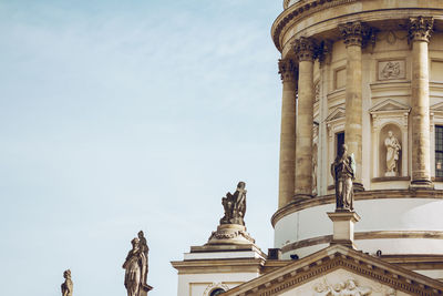 Low angle view of statues at neue kirche against sky in city