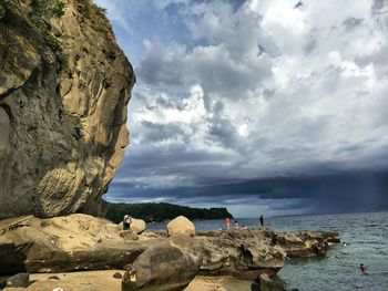 Scenic view of sea by cliff against sky