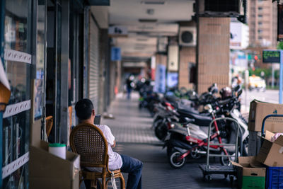 Rear view of woman sitting on street in city