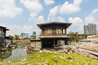 Abandoned building by lake against sky in city