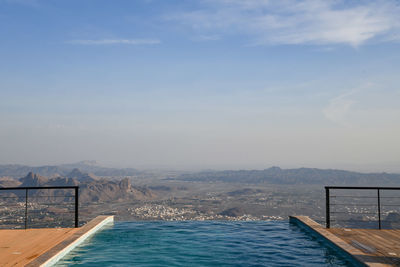 Swimming pool by sea against sky