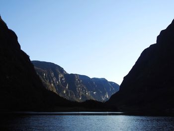 Scenic view of sea and mountains against clear blue sky