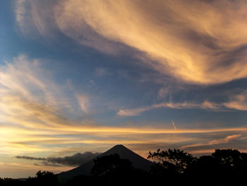 Scenic view of dramatic sky over silhouette mountains