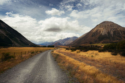 Road leading towards mountains against sky