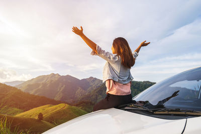 Full length of woman standing by car against sky