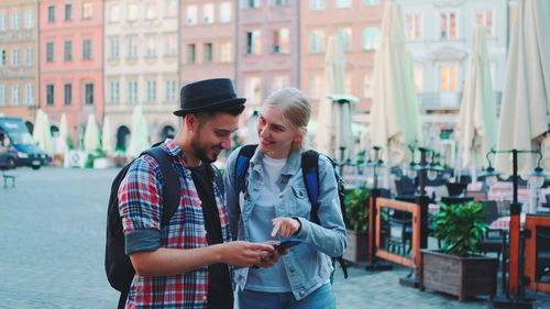 Side view of young woman holding hands while standing in city