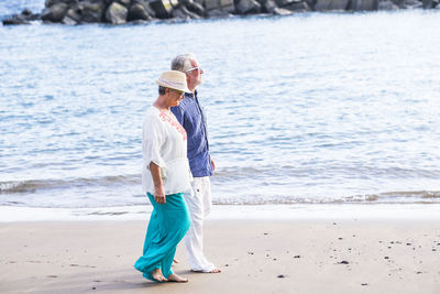 Side view of senior couple walking at beach