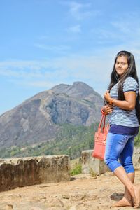 Full length of woman standing on mountain against sky