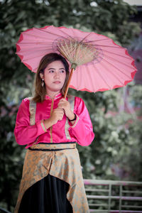 Portrait of young woman with umbrella standing outdoors