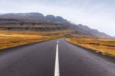 Empty road by mountain against sky