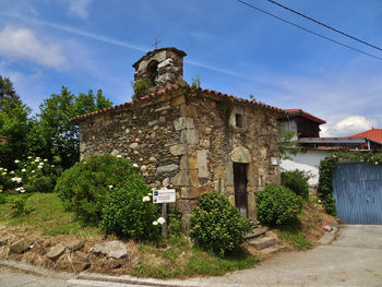 Old building by trees against sky