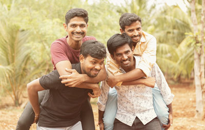 Portrait of friends standing against trees